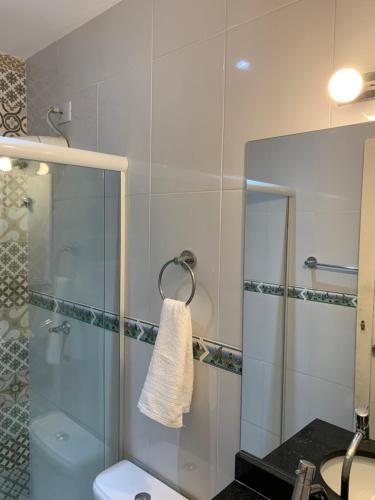 a bathroom with a glass shower with a toilet and a sink at Casa Aconchegante próximo da balsa in Ilhabela