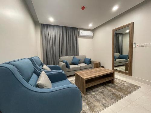 a living room with blue furniture and a mirror at روشن الماسي للشقق المخدومة in Yanbu