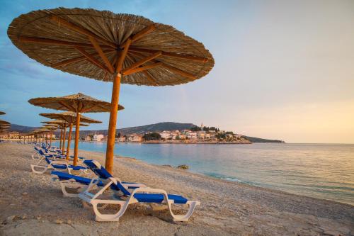 a group of chairs and umbrellas on a beach at Hotel Zora in Primošten