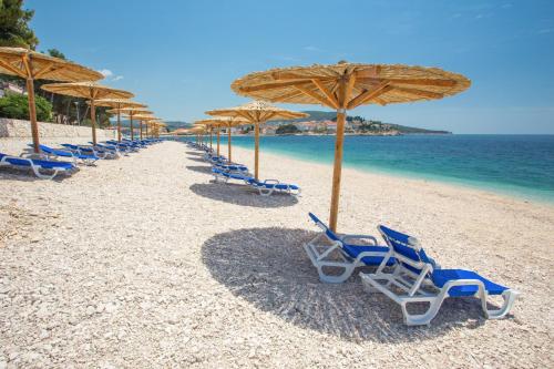 a row of chairs and umbrellas on a beach at Hotel Zora in Primošten