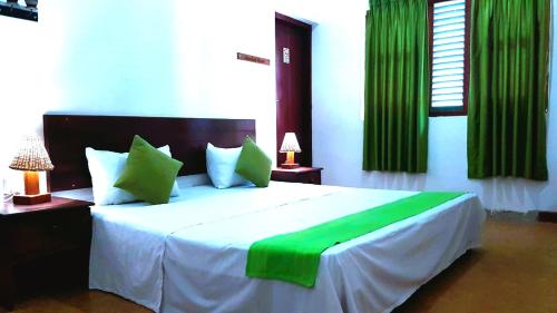 a bedroom with a large bed with green curtains at Villa 61 in Ambepussa