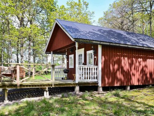 une petite cabine rouge avec une terrasse couverte et une terrasse dans l'établissement 4 person holiday home in Sl inge, à Ugglarp