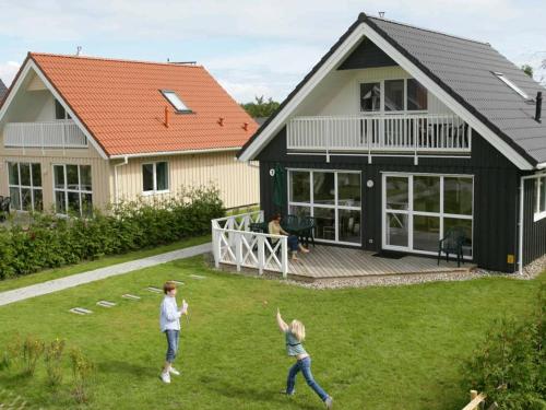 two people playing frisbee in the yard of a house at 8 person holiday home in Gelting in Gelting