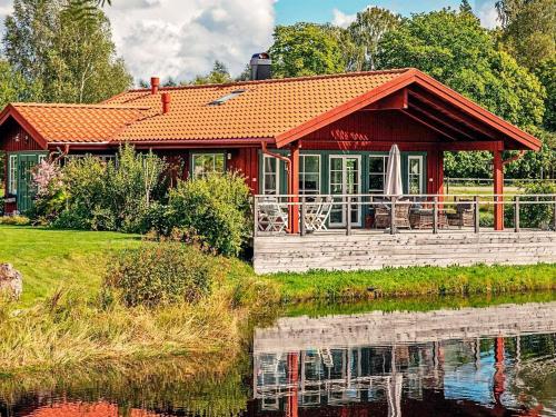 a red house next to a body of water at 6 person holiday home in BODAFORS in Västrahyn