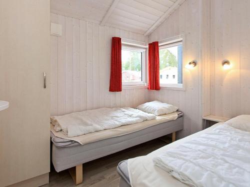 グレーミッツにあるThree-Bedroom Holiday home in Grömitz 15のベッドルーム1室(ベッド2台付)、赤いカーテン付きの窓が備わります。