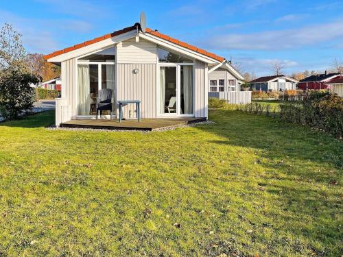 un pequeño cobertizo blanco con una silla en un patio en 4 person holiday home in GROEMITZ, en Grömitz