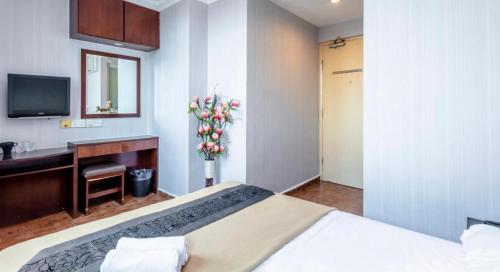 Dormitorio con cama, escritorio y TV en Hotel Duke, en Singapur
