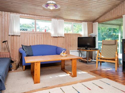 a living room with a blue couch and a tv at 6 person holiday home in Glesborg in Bønnerup