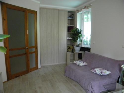 Guest House Dacha في كييف: غرفة معيشة مع أريكة أرجوانية مع وسادتين عليها