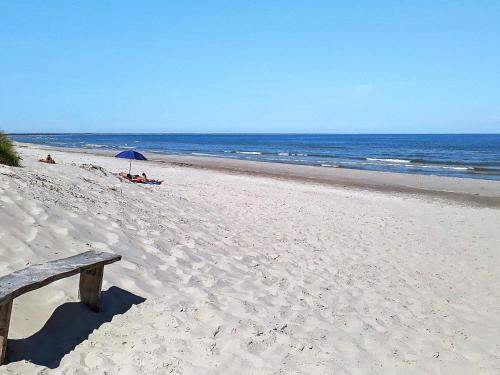 Strandbyにある5 person holiday home in Strandbyの砂浜の海辺に座るベンチ