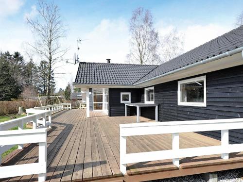 una casa con una terraza de madera frente a ella en 10 person holiday home in F rvang, en Fårvang