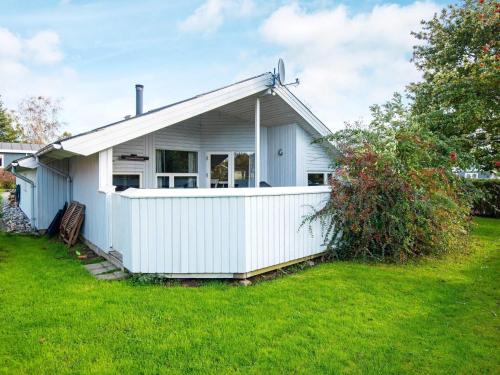 a white house with a fence in a yard at 8 person holiday home in Juelsminde in Sønderby