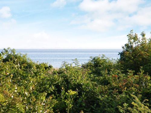 a view of the ocean from behind some trees at 10 person holiday home in Skjern in Lem