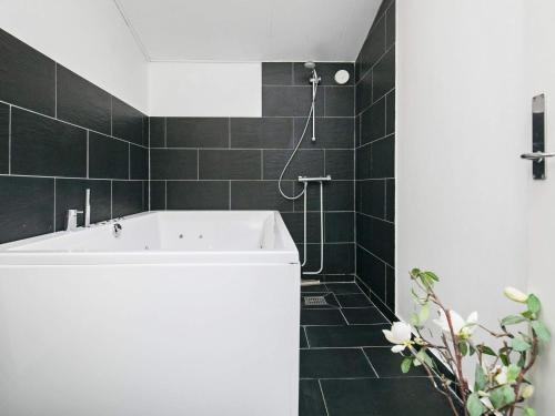 baño con bañera blanca y azulejos negros en 16 person holiday home in Brovst, en Brovst