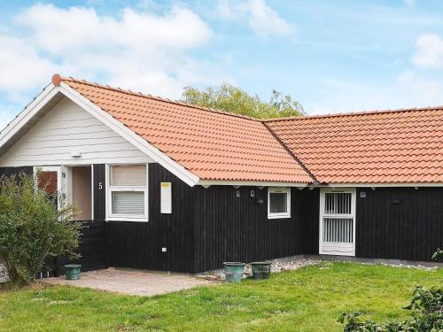 a black house with an orange roof at 5 person holiday home in R dby in Kramnitse