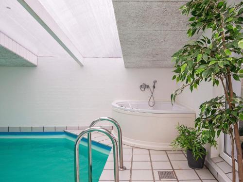 een badkamer met een bad naast een zwembad bij 14 person holiday home in rsted in Kare