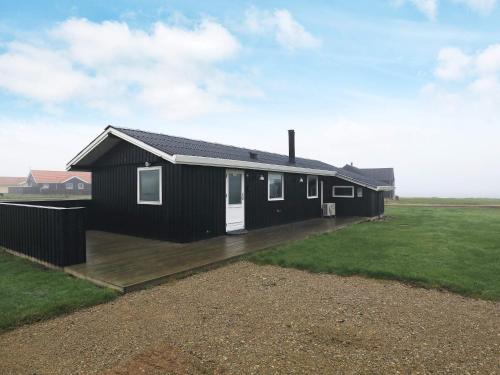 a black house with a deck in a field at 6 person holiday home in Vinderup in Vinderup