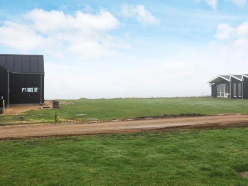 a small black building in a field with a dirt road at 6 person holiday home in Vinderup in Vinderup