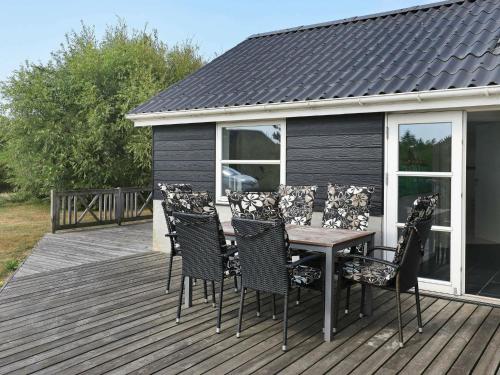 a wooden deck with a table and chairs on it at 8 person holiday home in Ulfborg in Fjand Gårde