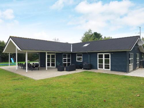a blue house with a patio and grass at 14 person holiday home in H jslev in Bøstrup