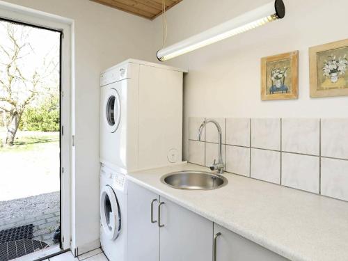 a kitchen with a sink and a washer and dryer at Six-Bedroom Holiday home in Væggerløse 3 in Marielyst