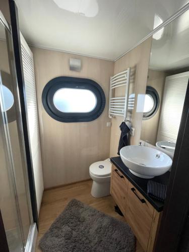 ein Badezimmer mit Waschbecken und Toilette und einem Fenster in der Unterkunft Hausboot Lore in Duisburg