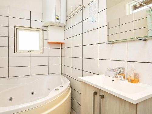 een witte badkamer met een bad en een wastafel bij Three-Bedroom Holiday home in Løkken 78 in Løkken