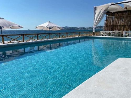 a large swimming pool with blue water and umbrellas at El Encanto Casa Boutique in Manzanillo