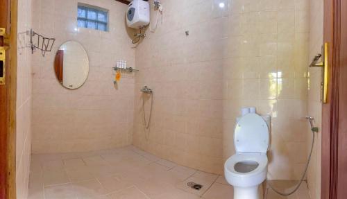 e bagno con servizi igienici e doccia con specchio. di Orange Balangan Bungalow a Uluwatu