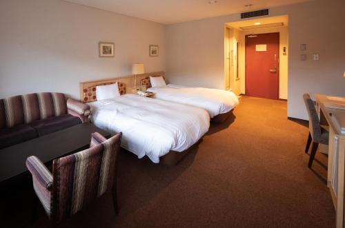 Habitación de hotel con 2 camas y sofá en 中津川温泉　ホテル花更紗, en Ochiai