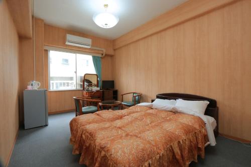 a bedroom with a bed and a desk and a window at Sun Flower City Hotel in Setouchi