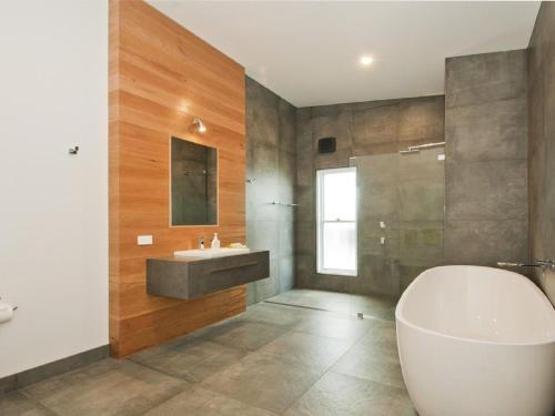 a bathroom with a white tub and a sink at Farrant House in Culburra Beach