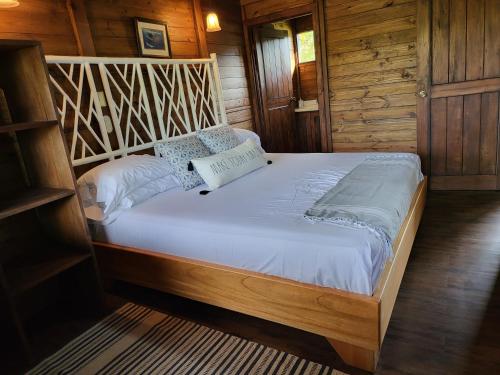 a large bed in a room with wooden walls at Private Mountaintop Cabin in Carara Biological Corridor 20 minutes to beaches in Carara
