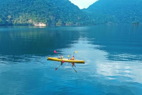 two people in a yellow kayak on a lake at Ba Be Lake View Homestay in An Ma