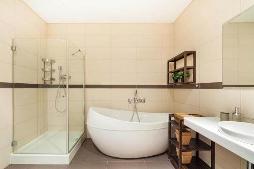 a bathroom with a tub and a glass shower at I Studios Moscow City in Moscow