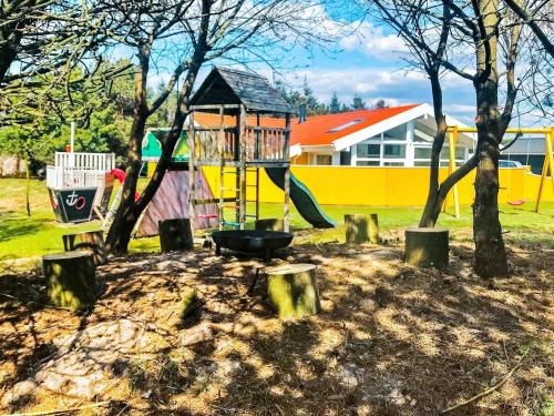 um parque infantil num parque com árvores e um edifício em 8 person holiday home in Vejers Strand em Vejers