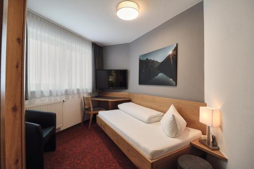 a hotel room with a bed and a desk at Hotel Garni & Aparthotel COLLINA in Ischgl