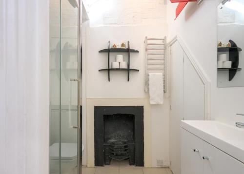 a fireplace in a bathroom with a sink and shelves at Delightful Bird Sisters Cottage with Free Parking in Brighton & Hove