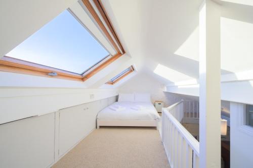 a attic bedroom with a bed and a skylight at Delightful Bird Sisters Cottage with Free Parking in Brighton & Hove