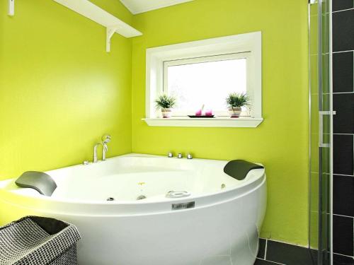 Holiday Home Amtsvej في Trend: حوض استحمام في حمام أخضر مع نافذة