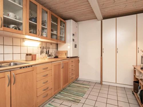 ルーケベングにある4 person holiday home in Rudk bingのタイルフロアのキッチン(木製キャビネット付)