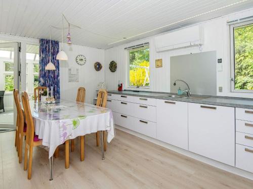 a white kitchen with a table and chairs at 6 person holiday home in Ringk bing in Nørby