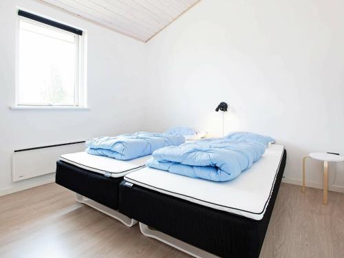 um quarto branco com uma cama com almofadas azuis em Holiday Home Ankersholm em Rødby