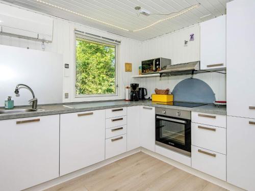 a white kitchen with white cabinets and a window at 6 person holiday home in Ringk bing in Nørby