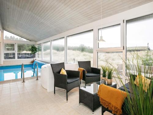 eine Terrasse mit einem Pool, Stühlen und einem Tisch in der Unterkunft 12 person holiday home in L kken in Grønhøj