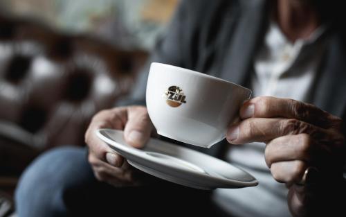 ツヴァイブリュッケンにあるHotel Rosengartenの白いカップとオーサーを持っている人