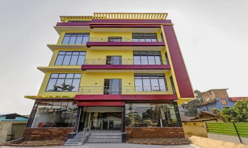 a tall yellow and purple building with glass windows at Treebo Trend Hotel Mobi VIP Airport in Guwahati