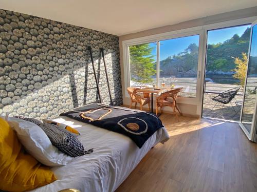 a bedroom with a bed and a table and windows at Les Villas de la Plage in Névez