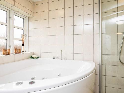 a white bath tub in a white tiled bathroom at Holiday home Humble in Humble