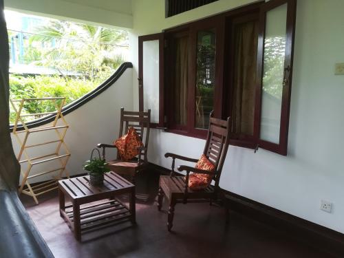 a porch with two rocking chairs and a table at The Hideout Sigiriya in Sigiriya